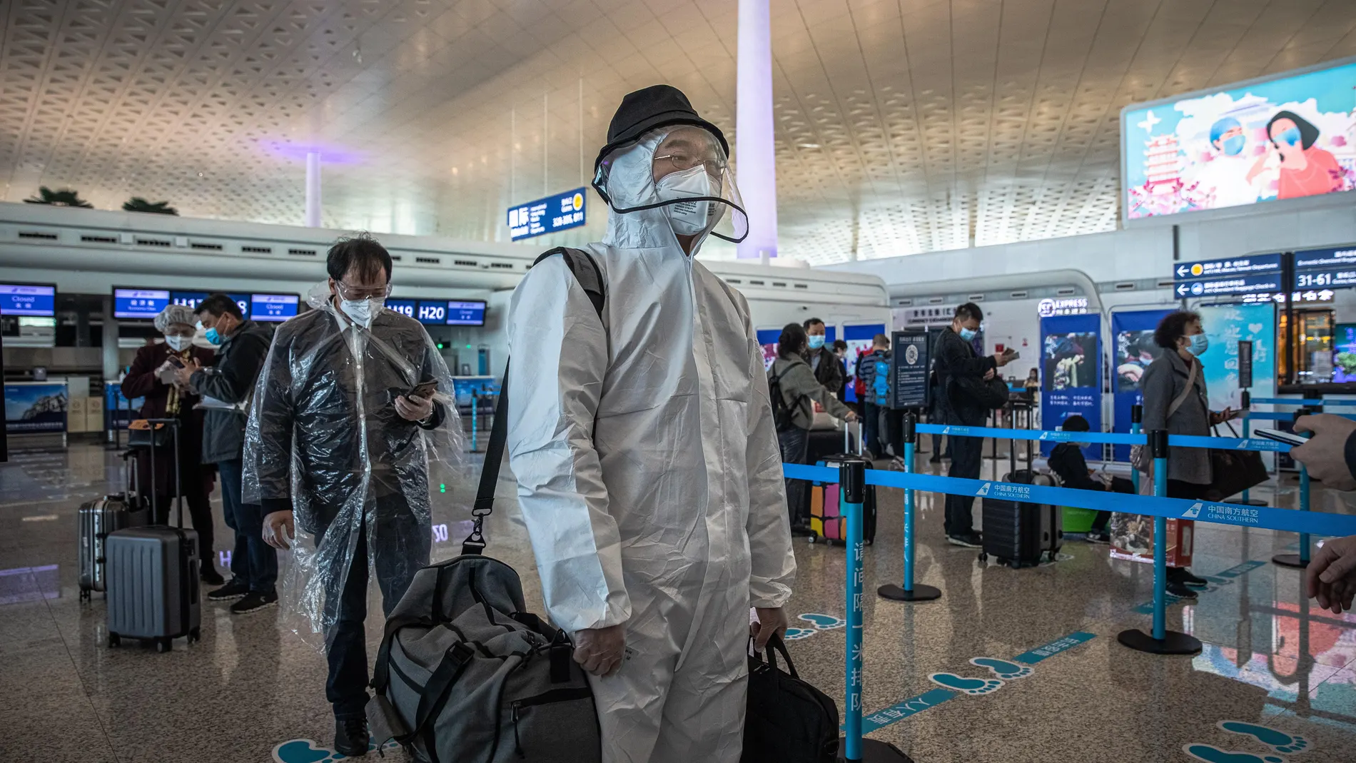 Un hombre ataviado con mono blanco para tomar un avión hoy en el aeropuerto de Wuhan