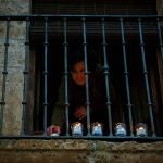 Una mujer enciende velas en una ventana de la localidad burgalesa de Sotillo de la Ribera, en la que se debería haber celebrado la procesión de "La Carrera"