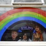 Una familia se asoma a la ventana de su casa en Londres, decorada con un arcoiris/EFE