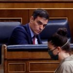 Spain's Prime Minister, Pedro Sanchez looks at far-right Vox party's deputy Macarena Olona wearing a mask to protect against coronavirus, during the opening of a parliamentary session in Madrid, Spain, Thursday, April 9, 2020. Sanchez acknowledged that Spain's government, and its regions which administer health services, were caught off guard by the crisis and left its hospitals woefully short on critical supplies, including virus tests and protective clothing for medical workers. (Mariscal, Pool Photo via AP)