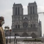 Desgracia sobre desgracia. Un parisino con mascarilla por el coronavirus pasa por delante de lo que queda de Notre Dame