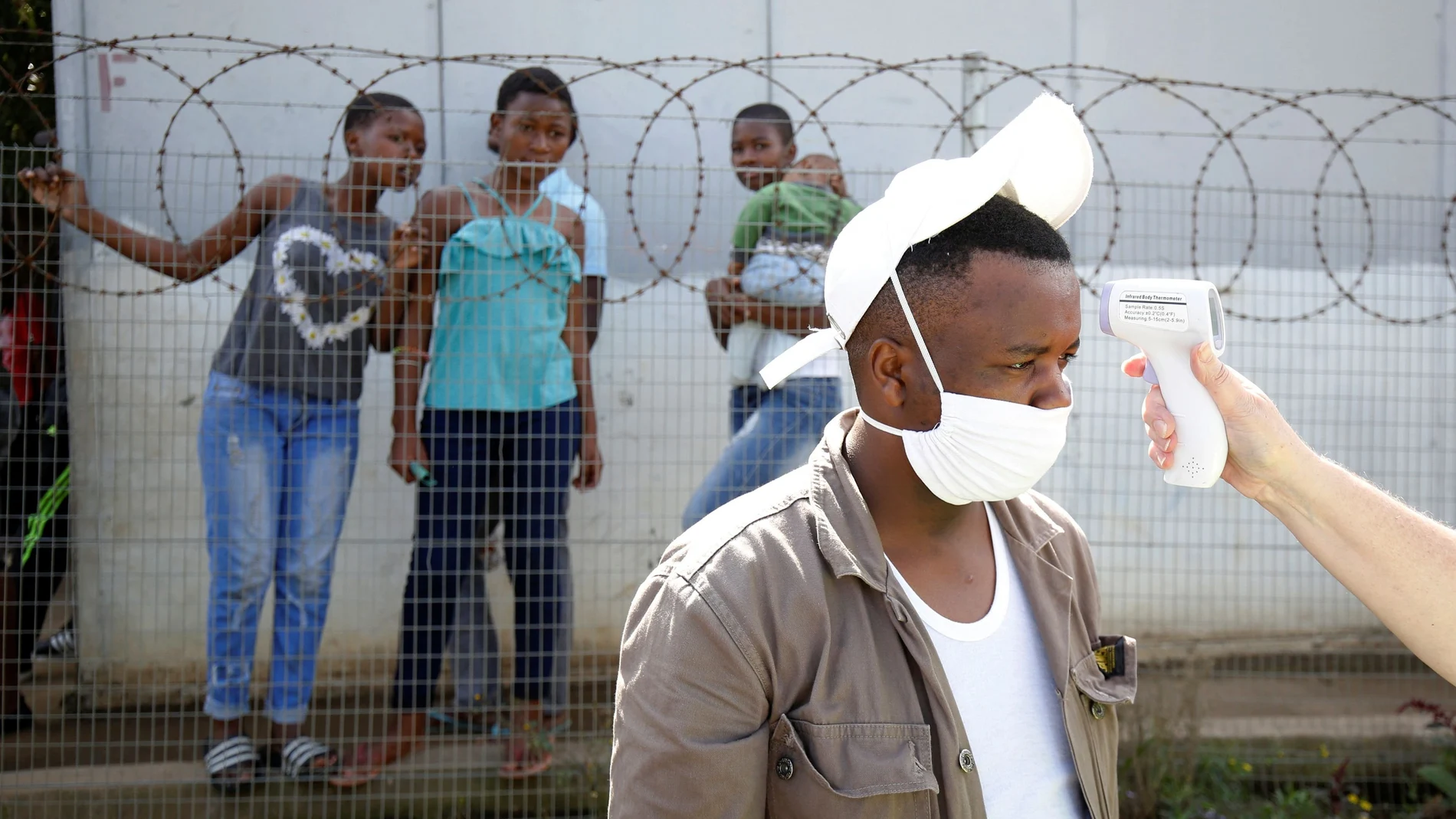 A health worker checks a mans temperature during door to door screening in an attempt to contain the coronavirus disease (COVID-19) outbreak in Jika Joe informal settlement in Pietermaritzburg