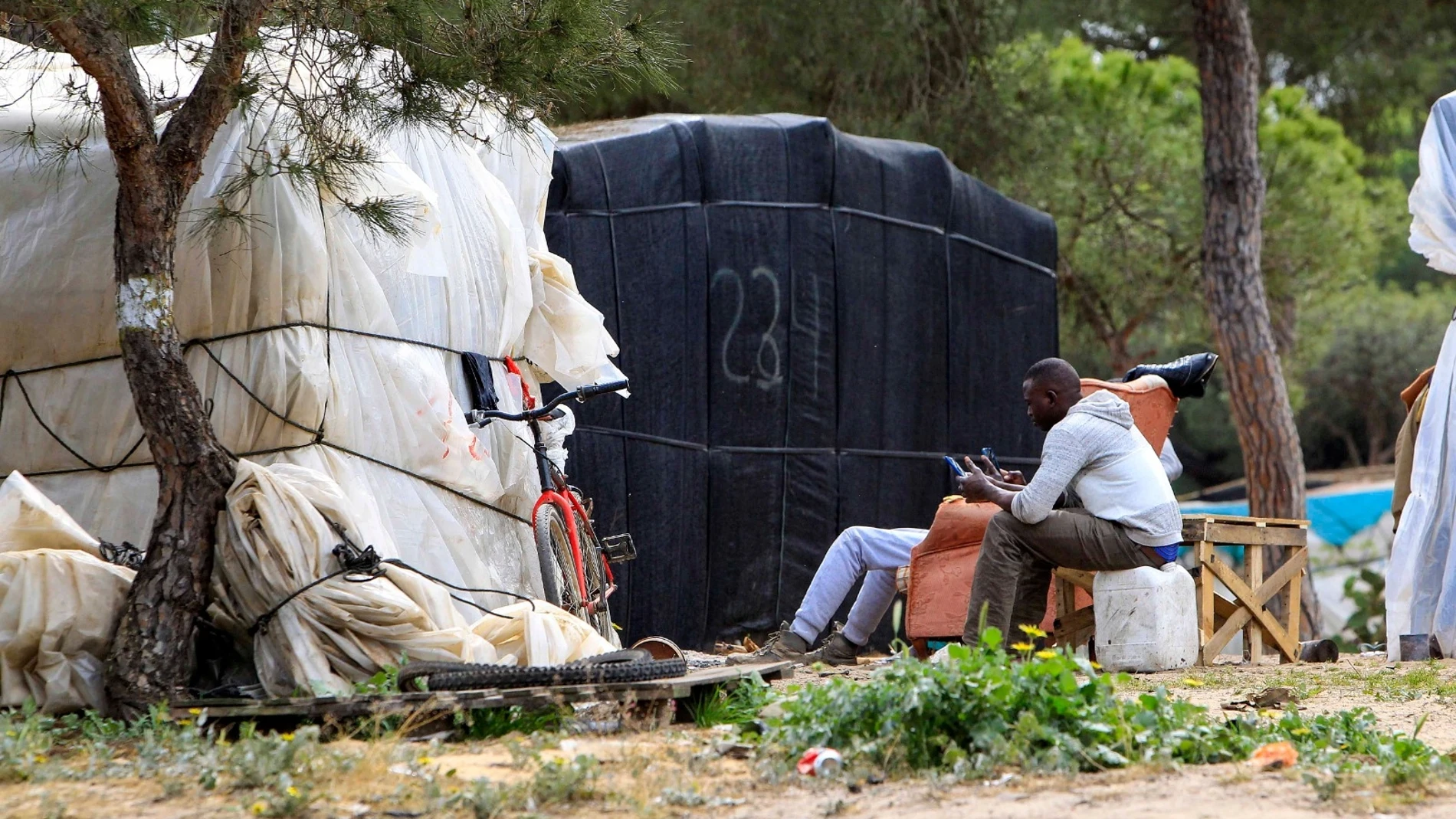 Un grupo de inmigrantes a las puertas de una chabola, en un asentamiento de Moguer