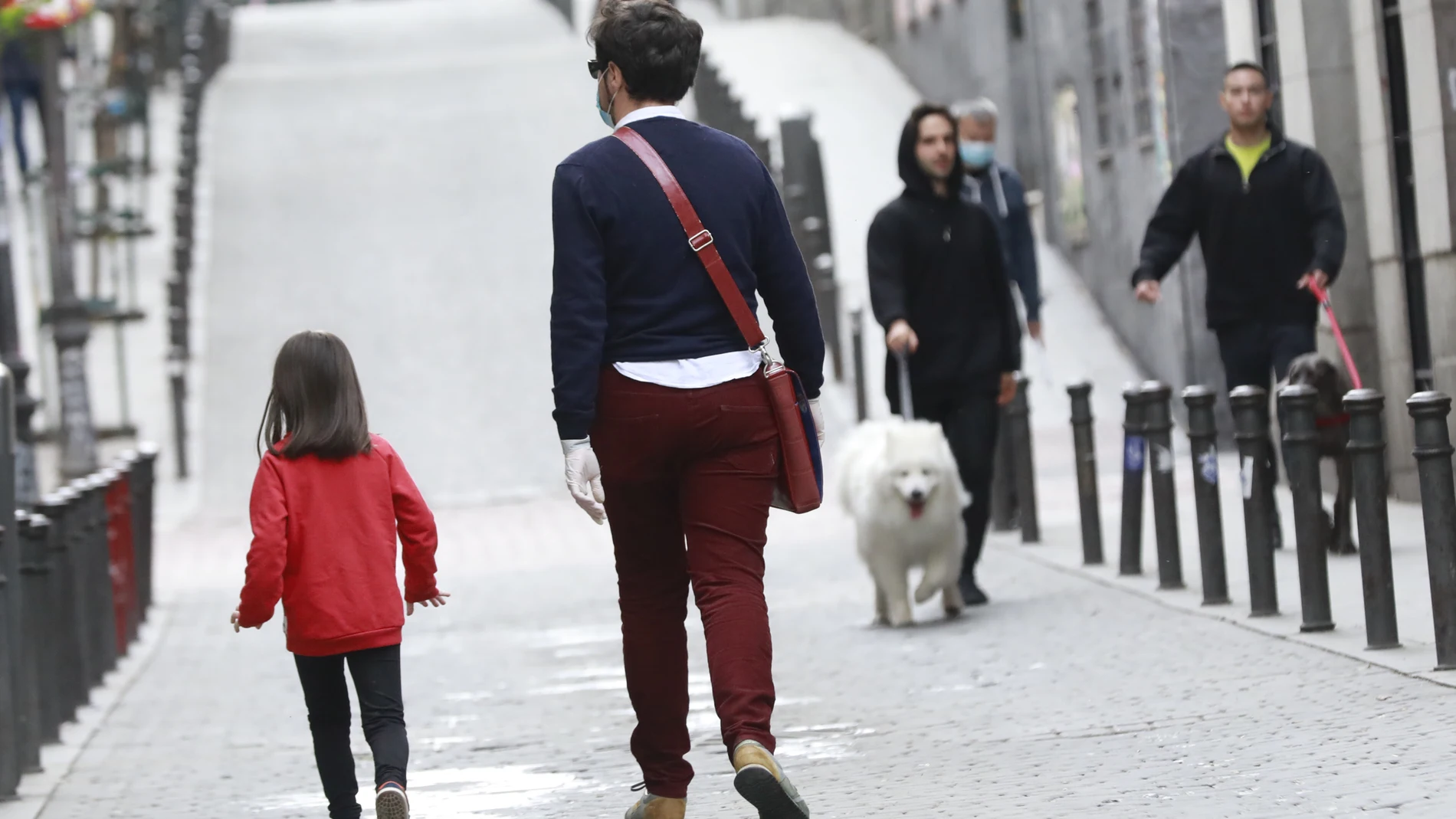 Una niña pasea hoy con un adulto por Madrid