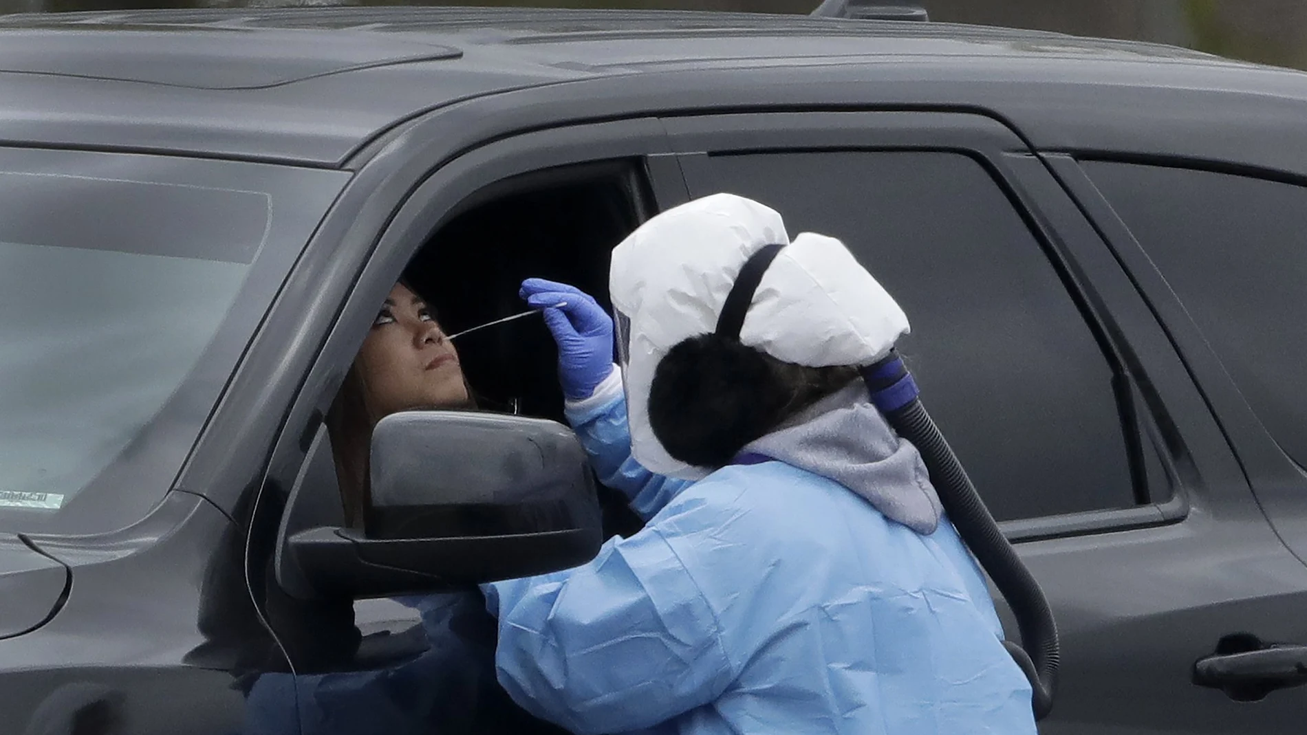 Healthcare workers from Johnson County Health & Environment test a woman for COVID-19 at a drive-in testing center Friday, April 17, 2020, in Shawnee, Kan. Kansas Democratic Gov. Laura Kelly, whose state has one of the lowest per capita testing rates in the country, told CNN it has been difficult to get testing supplies. (AP Photo/Charlie Riedel)