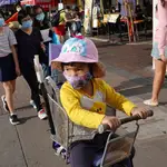 Una pequeño con mascarilla acompañado por sus padres en una calle de Hong Kong