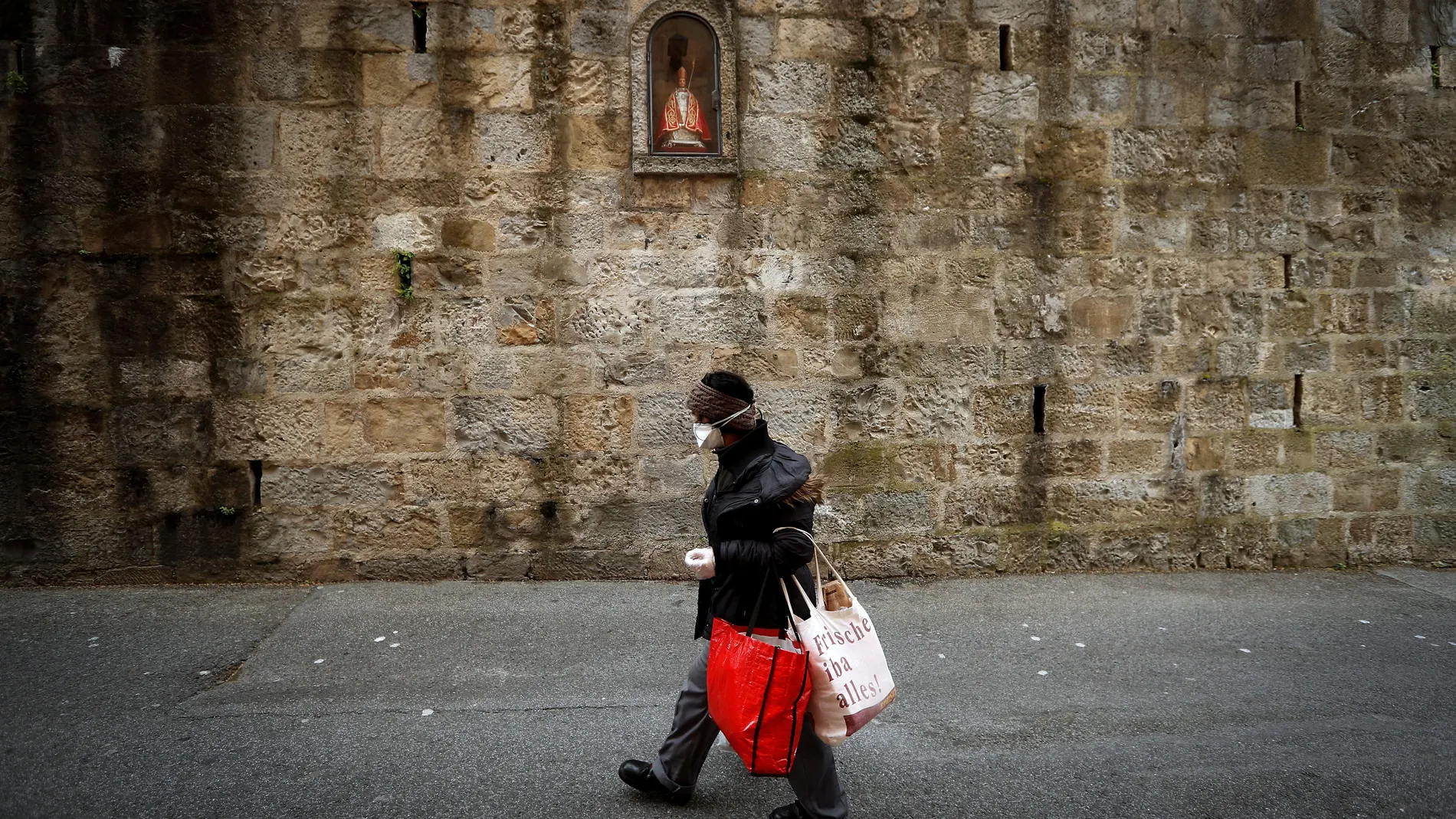 Una mujer pasa por delante de la hornacina de San Fermín en la cuesta de Santo Domingo de Pamplona, tras conocerse la suspensión de las fiestas de 2020