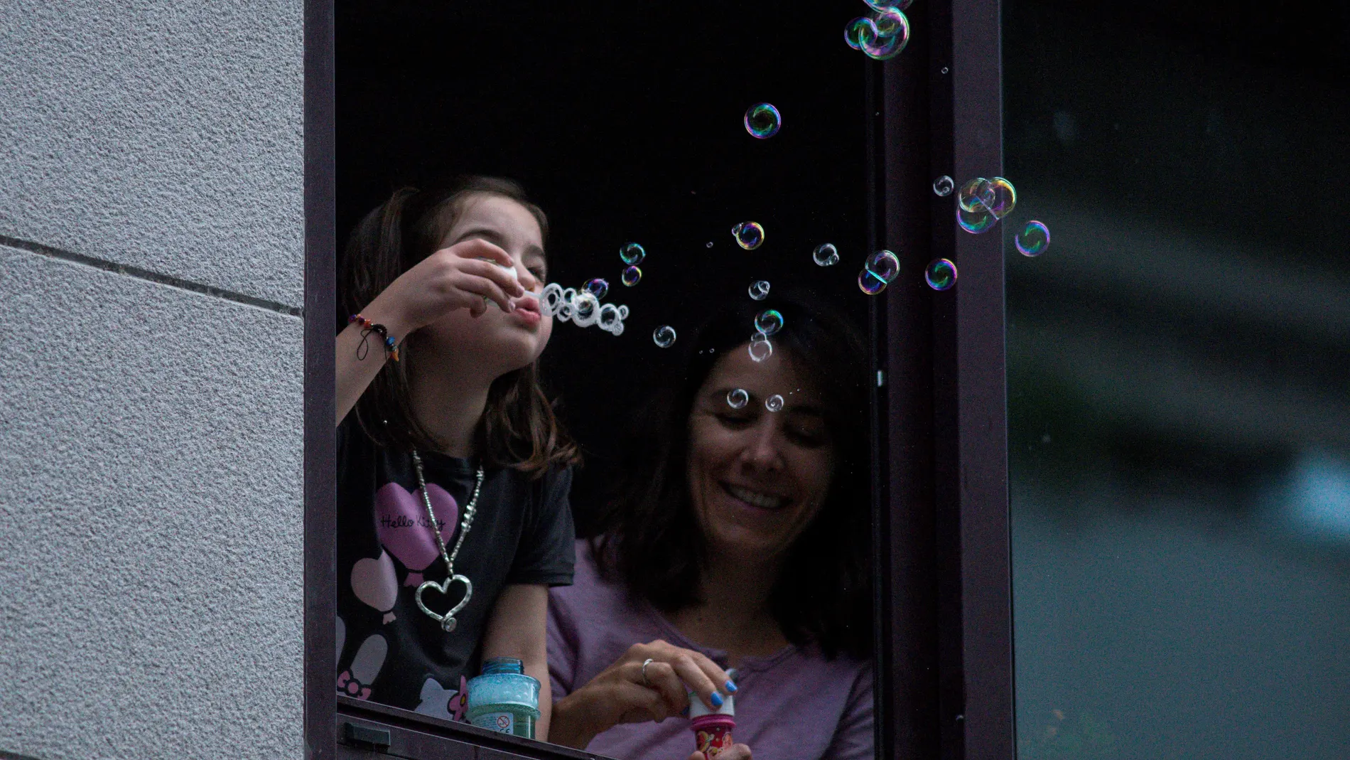 Una niña hace pompas de jabón en una ventana de su vivienda, hoy martes en Ourense. Los niños de hasta 14 años podrán salir a partir del 26 de abril a dar paseos, con lo que el Gobierno rectifica la medida aprobada esta misma mañana.