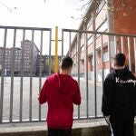 Dos adolescentes observan el patio cerrado de un colegio