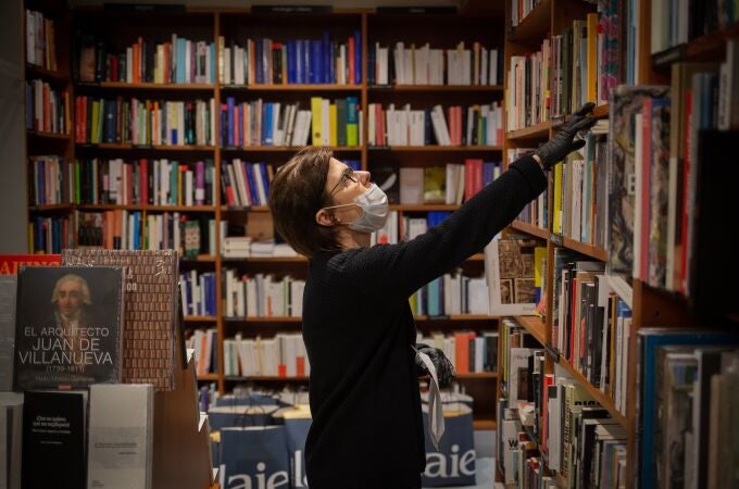 Un trabajadora de la librería Laie Pau Claris librería-café ubicada en la calle catalana de Pau Claris, coloca libros y material en las estanterías del local