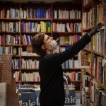 Un trabajadora de la librería Laie Pau Claris librería-café ubicada en la calle catalana de Pau Claris, coloca libros y material en las estanterías del local