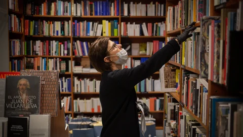 Un trabajadora de la librería Laie Pau Claris librería-café ubicada en la calle catalana de Pau Claris, coloca libros y material en las estanterías del local