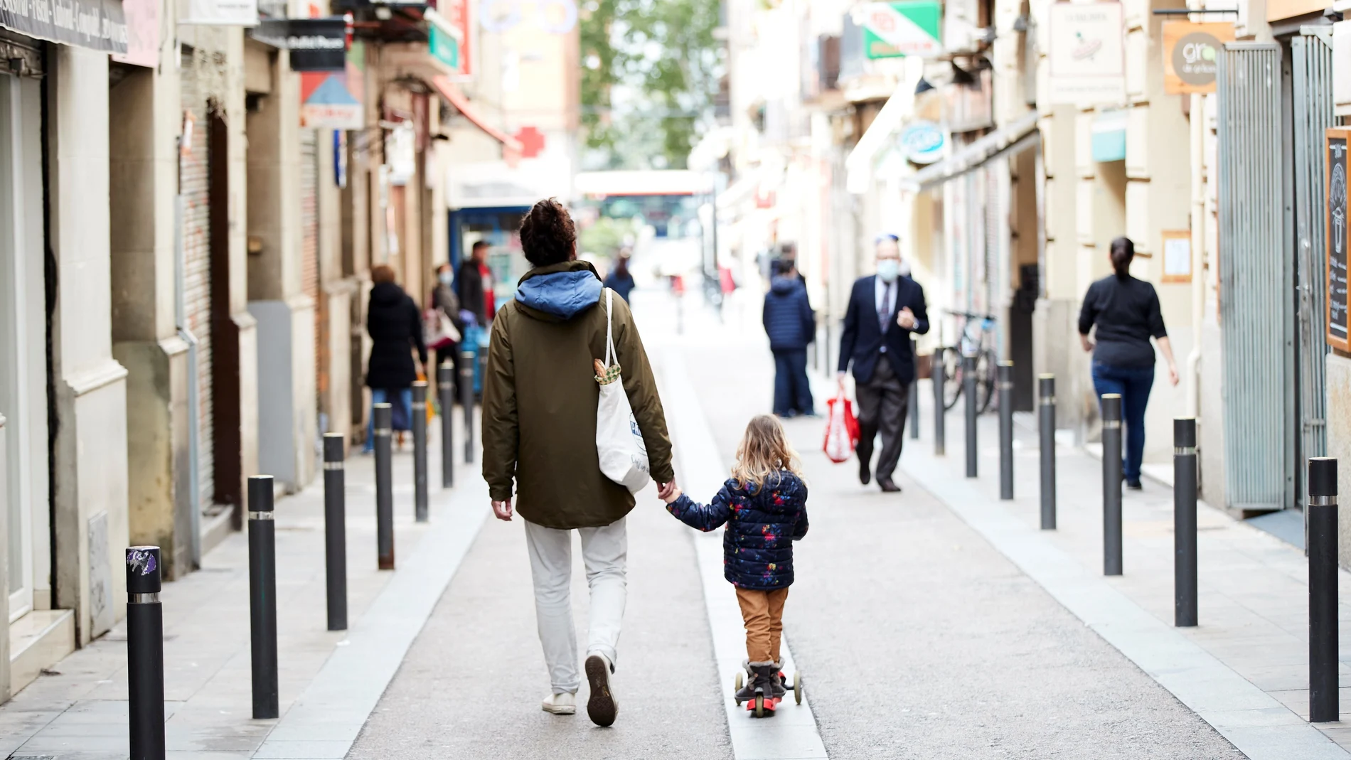 Un hombre y una niña caminan por el barrio de Gracia de Barcelona