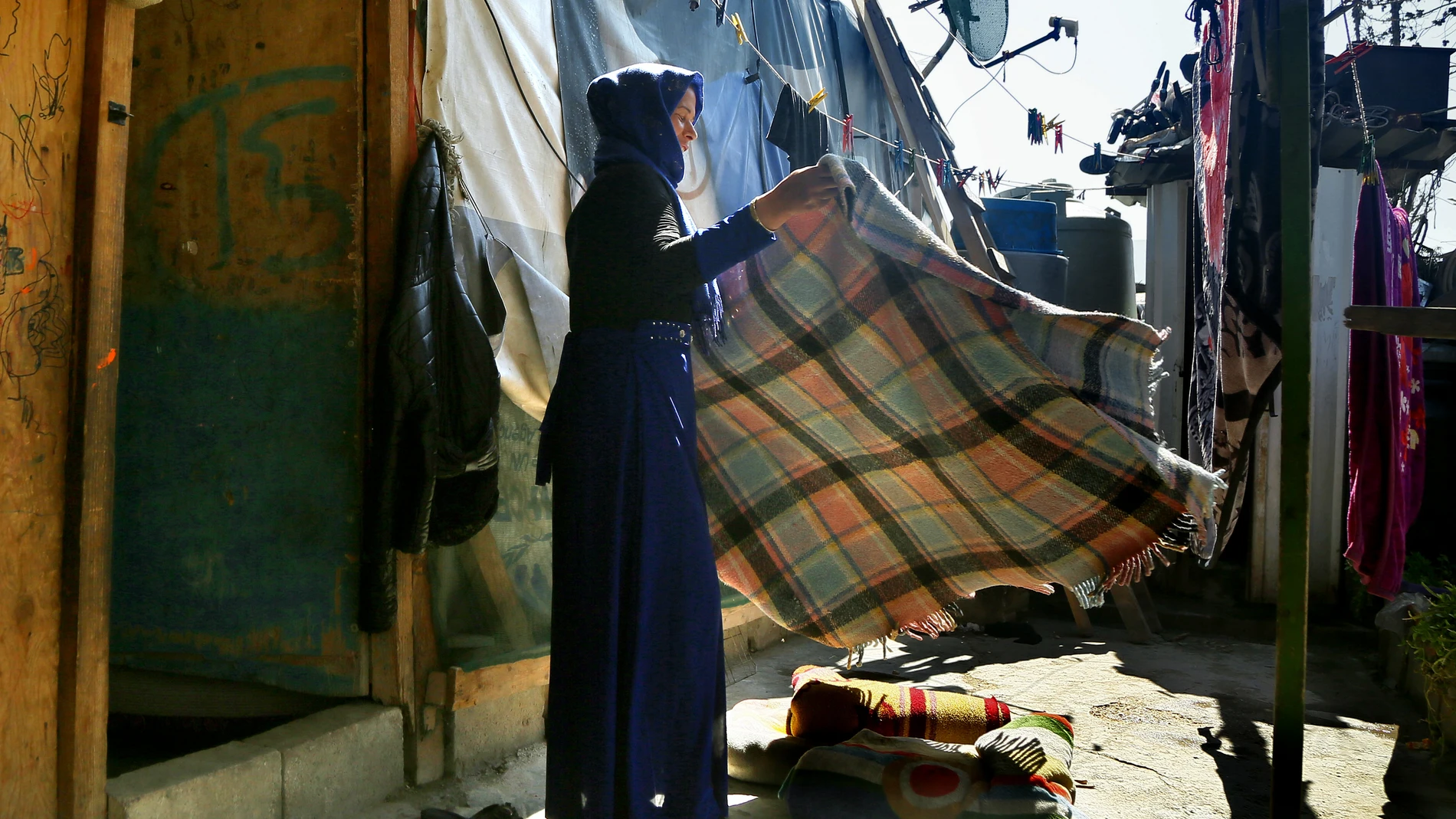 Una refugiada siria, madre de cinco hijos, tiende una manta en el campo de refugiados de Abu Fares, en el Valle de la Bekaa