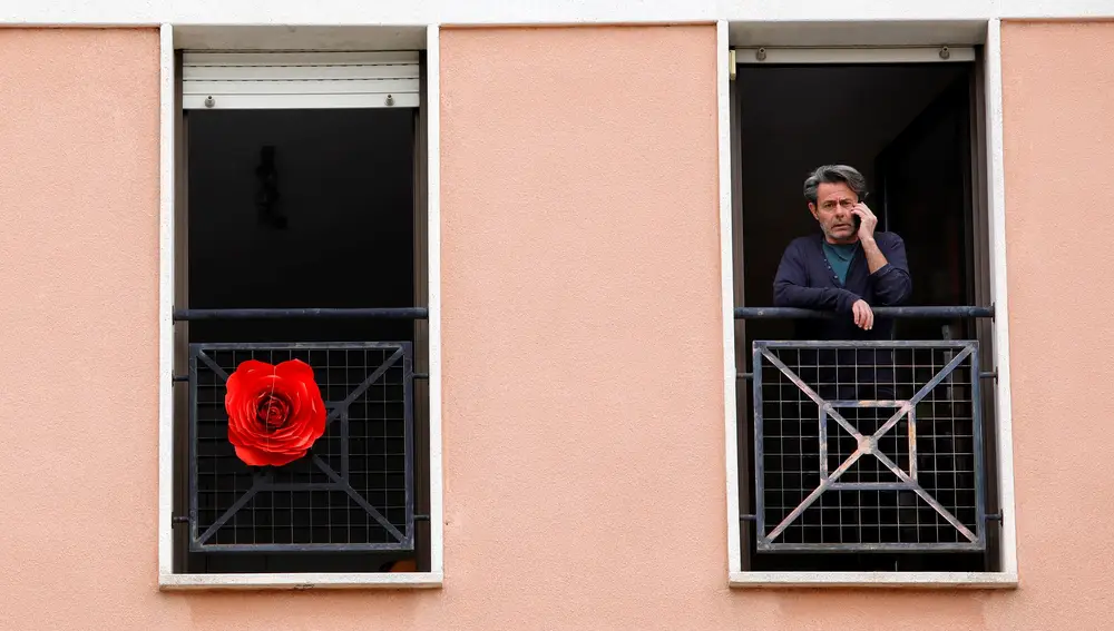 Un hombre en su balcón cuando se cumplen cuarenta días del estado de alarma y Cataluña vive una atípica celebración de la fiesta de Sant Jordi