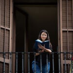 Una joven lee un libro en el balcón de su casa