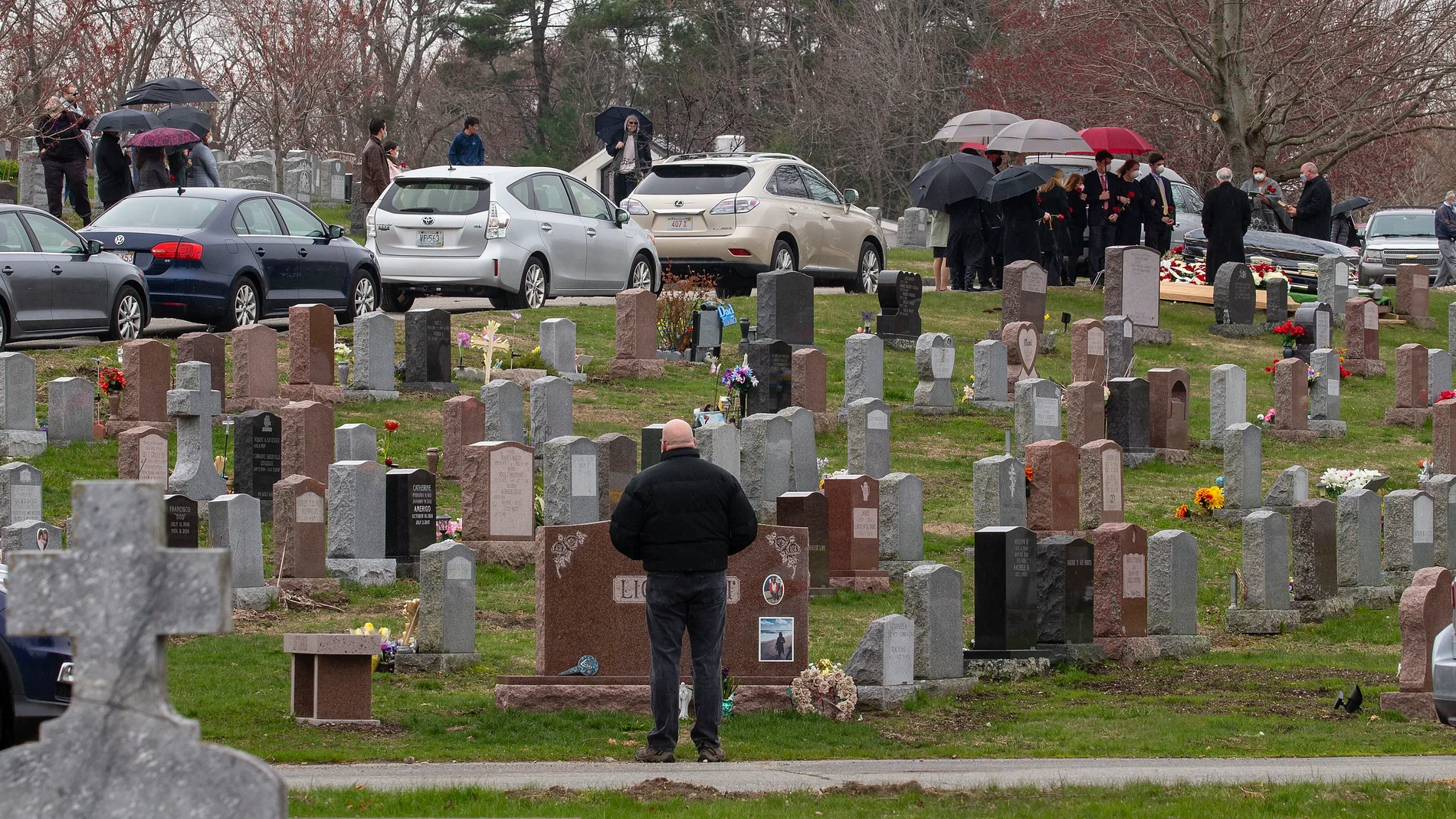 Familiares de fallecidos por el Covid-19 mantuenen la distancia social en el cementerio de Lawrence, Massachusetts,