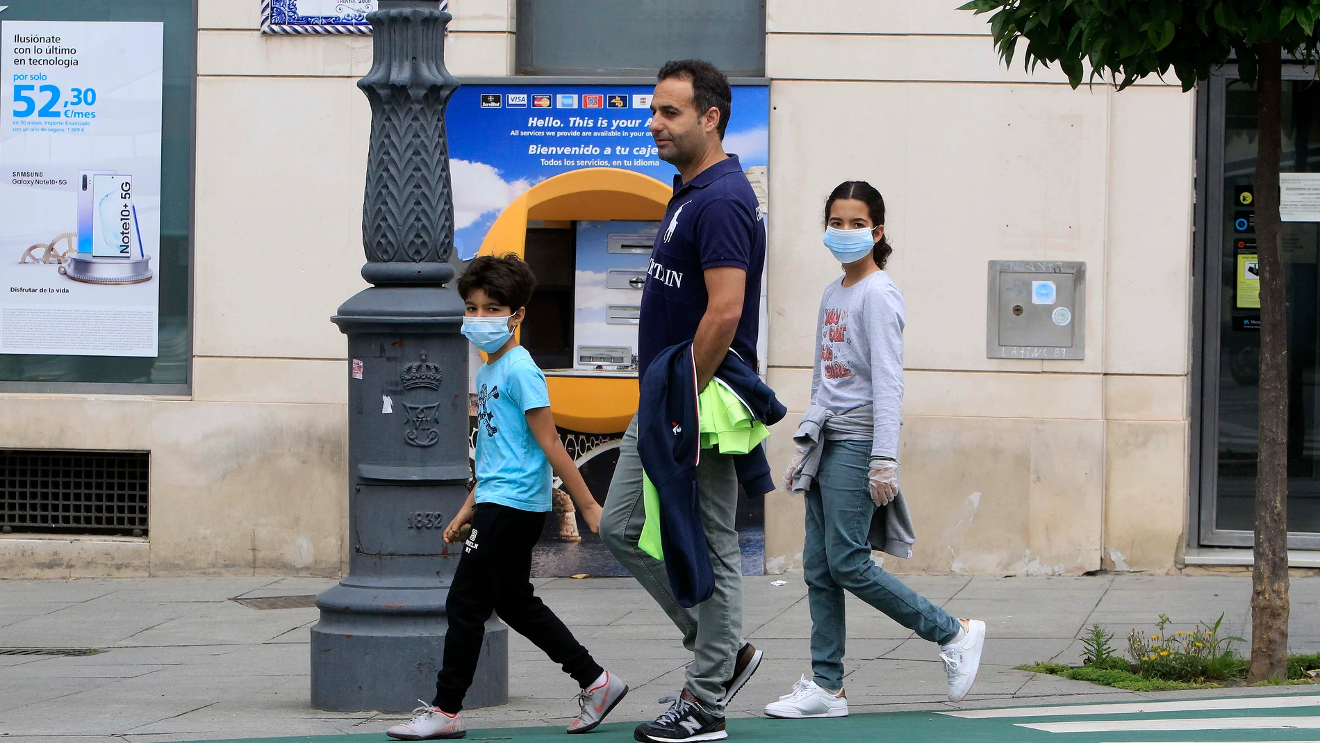 Un hombre pasea con sus hijos, protegidos con mascarilla