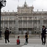 Unos padres con sus hijos pasean delante del Palacio Real en Madrid, este domingo en el que más de seis millones de niños menores de 14 años pueden salir a la calle