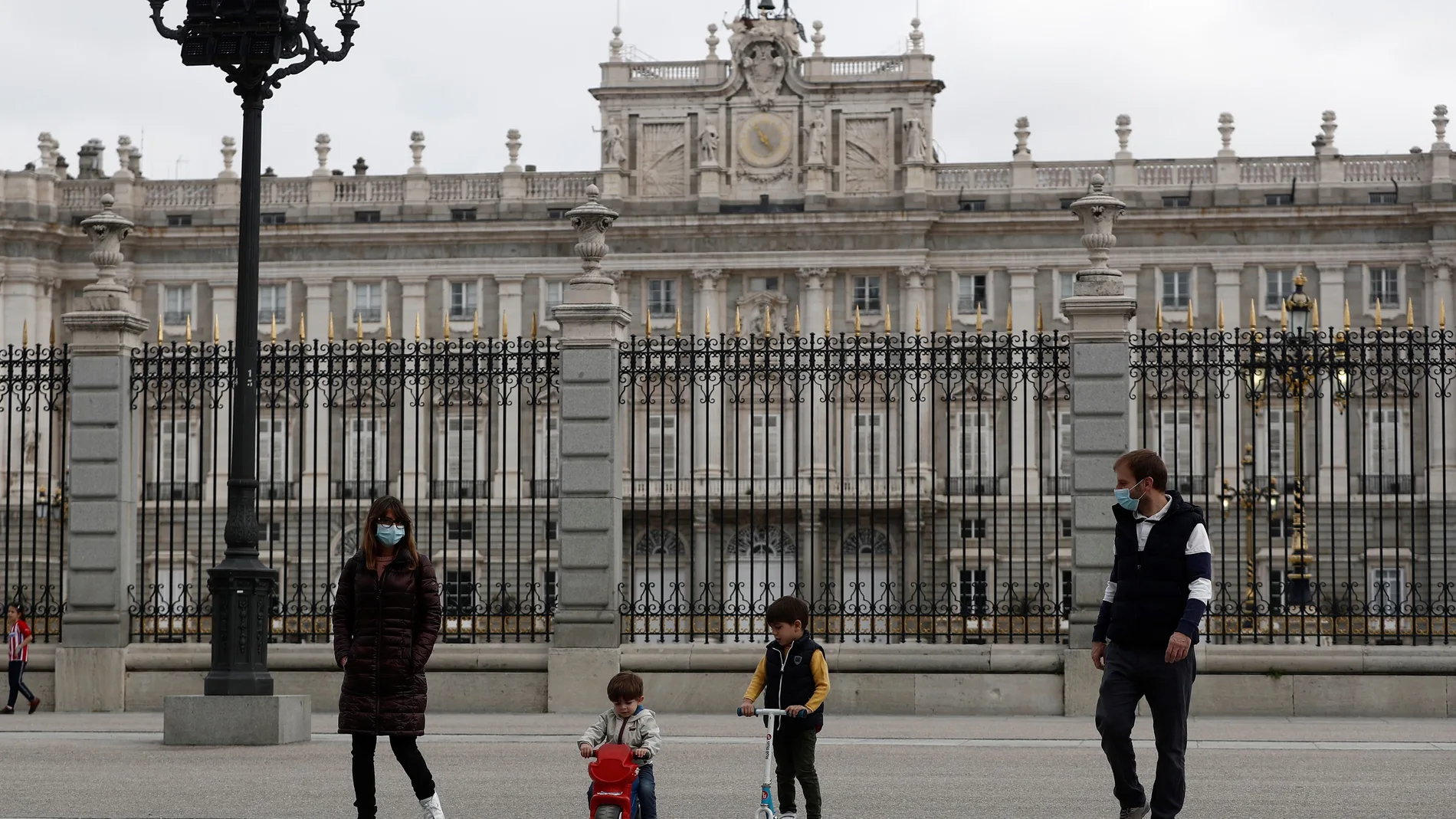 Unos padres con sus hijos pasean delante del Palacio Real en Madrid, este domingo en el que más de seis millones de niños menores de 14 años pueden salir a la calle