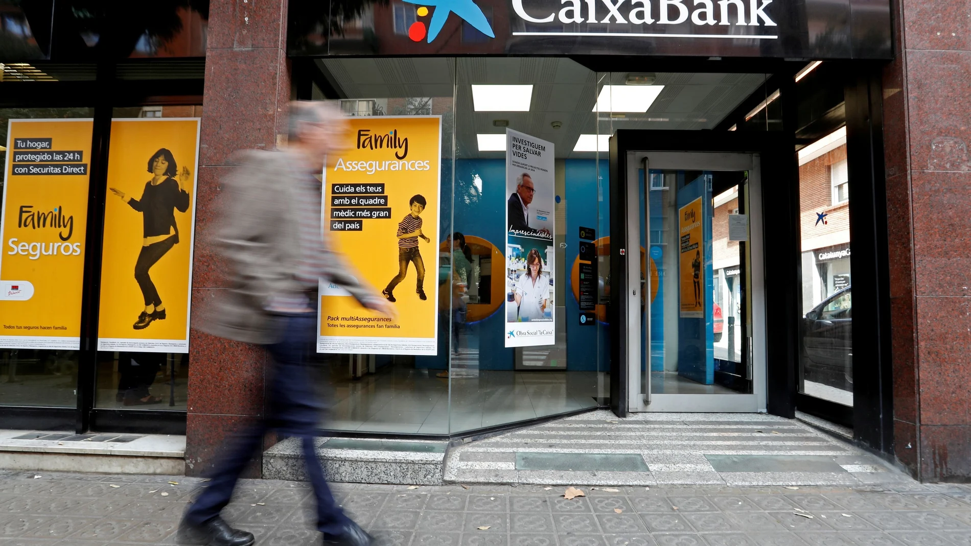 FILE PHOTO: A man walks past a Caixa bank branch in Barcelona