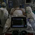 Personal sanitario totalmente protegido atiende a un paciente ingresado en la Unidad de Cuidados Intensivos del Hospital Infanta Sofía en San Sebastián de los Reyes