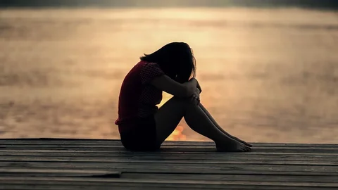 Una persona posa su cabeza sobre sus rodillas, en señal de tristeza