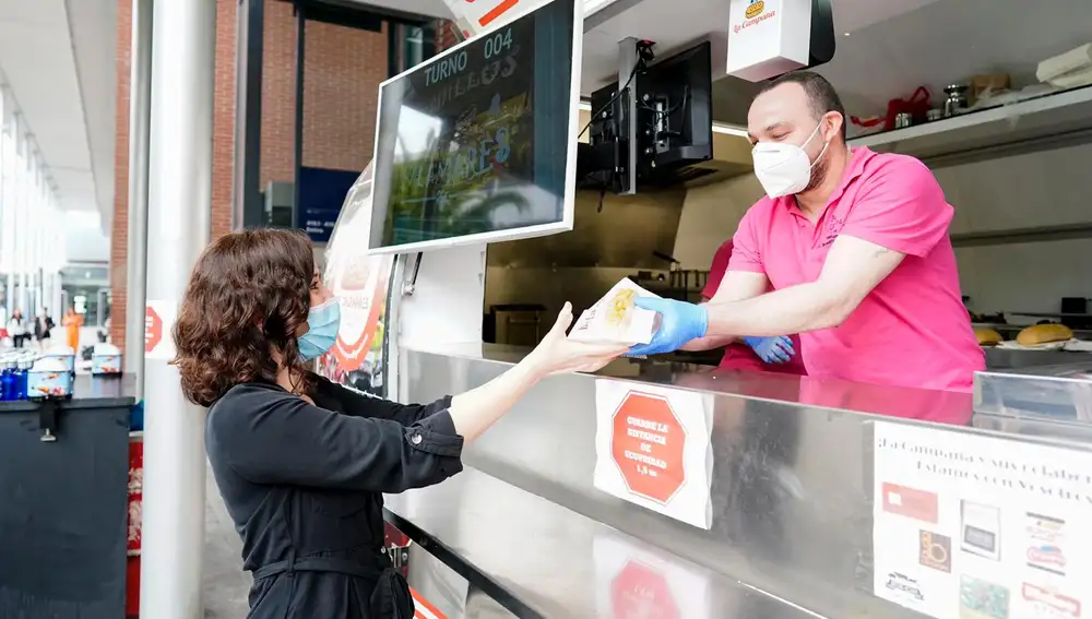 Díaz Ayuso toma un bocadillo de calamares de un foodtruck de Ifema