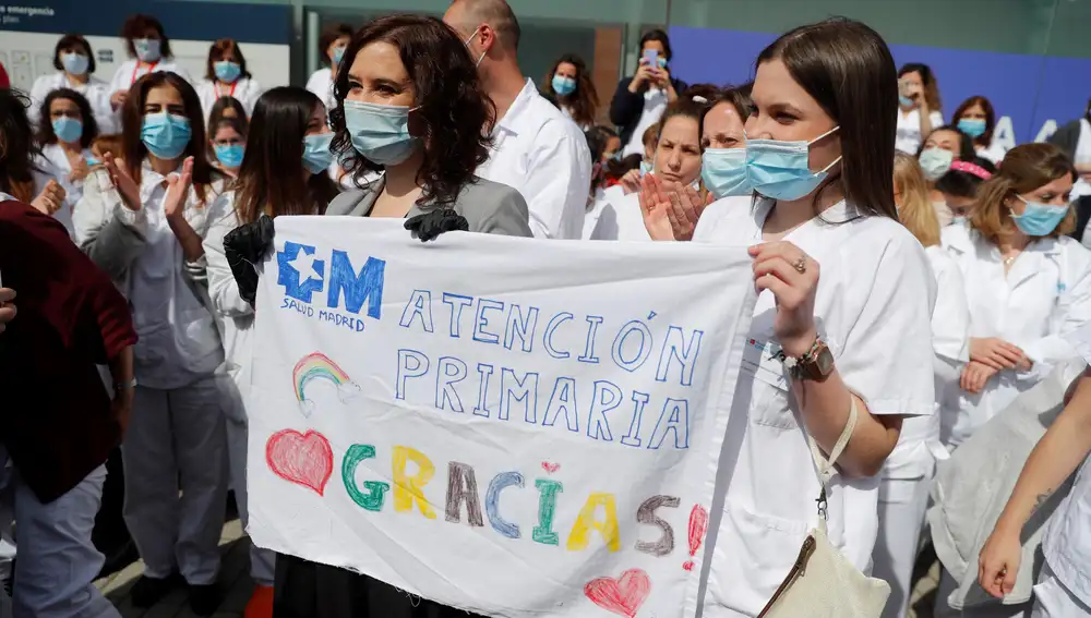 La presidenta de la Comunidad de Madrid, Isabel Díaz Ayuso, sostiene una pancarta junto una sanitaria durante el acto de cierre del hospital de campaña del recinto ferial de Ifema