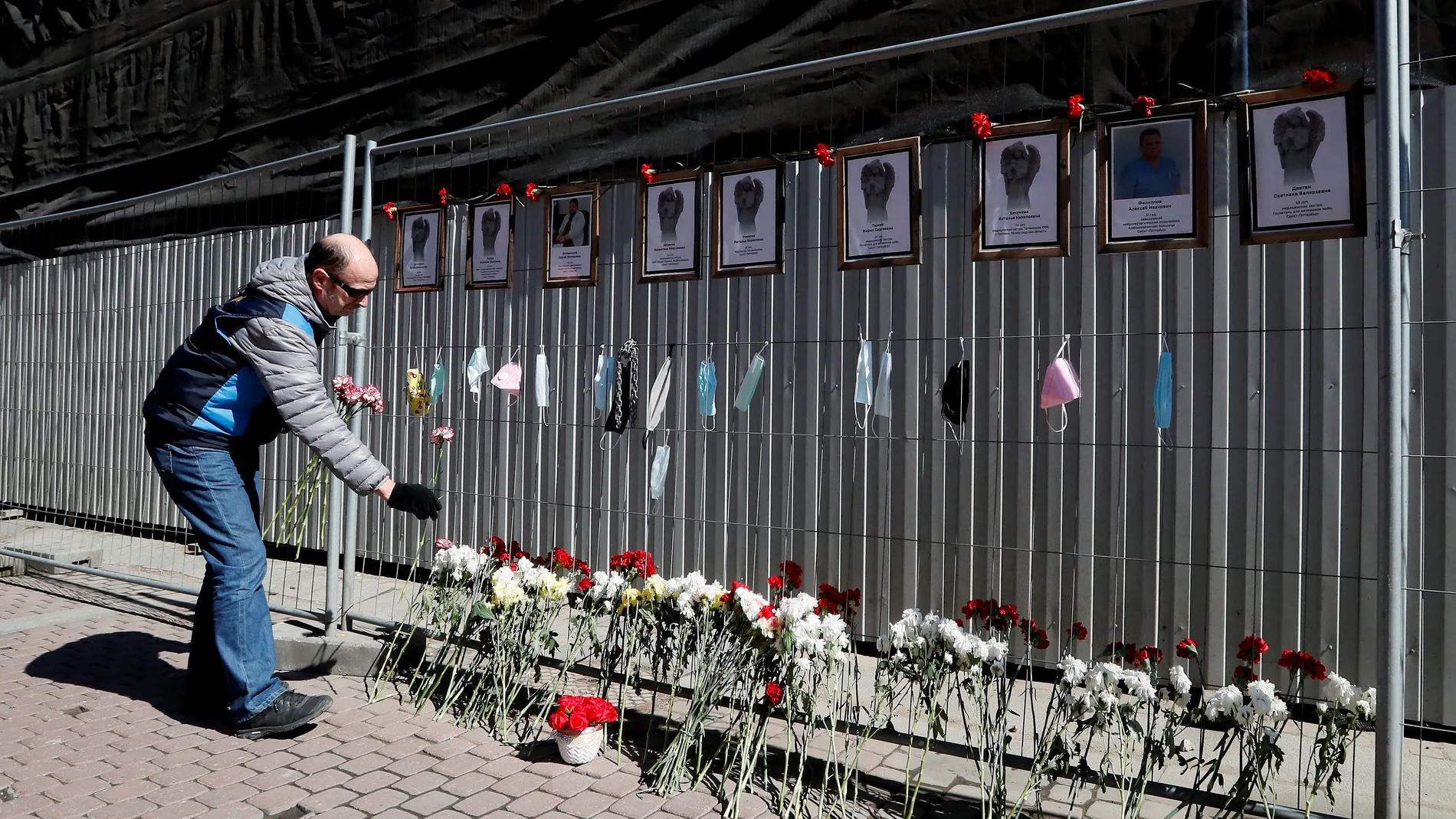 Un hombre deposita flores como homenaje a los sanitarios fallecidos a causa del coronavirus en un memorial improvisado frente a un hospital del centro de San Petersburgo.