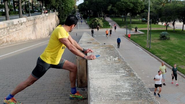 GRAFCVA4660. VALENCIA, 02/05/2020.- Un deportista realiza estiramientos mientras contempla el flujo de deportistas en el antiguo cauce del Turia dentro de la nueva normativa decretada por el Gobierno que permite hacer deporte o salir a pasear en dos franjas horarias. EFE/Kai Försterling