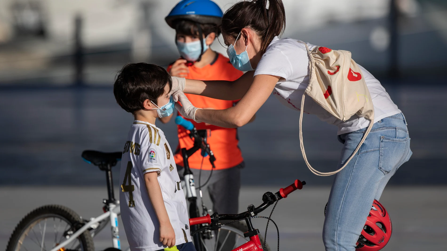 Una madre coloca unas mascarillas a sus hijos