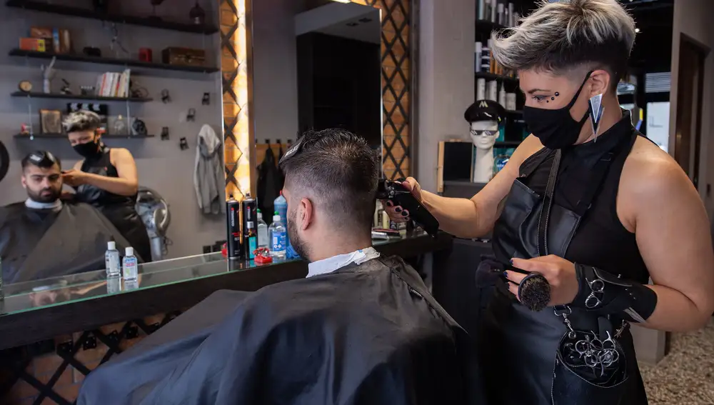 Una peluquera con mascarilla corta el pelo a su cliente en Tesalónica