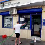 El dueño de un establecimiento de loterías, limpia y prepara su negocio. EFE/A.Carrasco Ragel