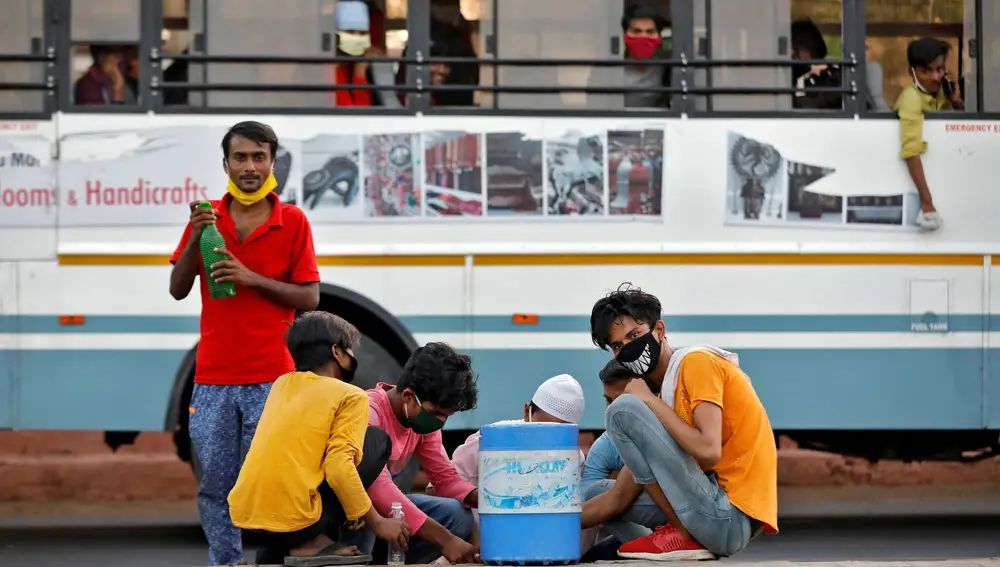 Trabajadores migranets que se habían quedado varados en el estado de Gujarat beben agua anates de seguir su viaje hacia Bihar, en Ahmedabad, India