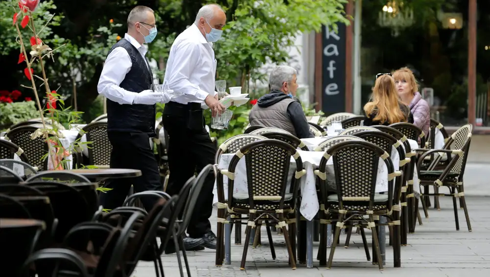 Camareros con mascarillas sirven en una terraza de Belgrado