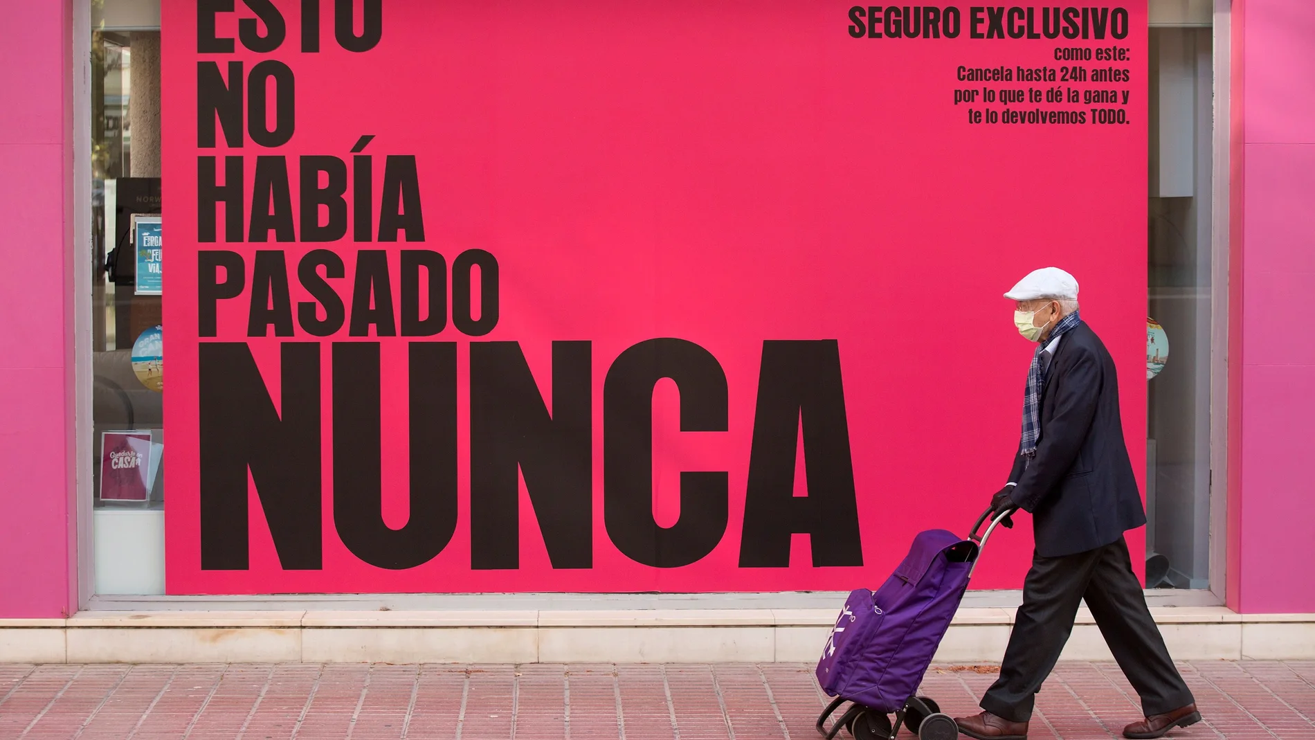 Una persona protegida con una mascarilla pasa por delante de una agencia de viajes en Málaga