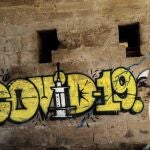 Una persona con mascarilla pasa ante un grafiti en Valencia