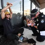 Un agente expedienta durante una protesta a un solicitante de asilo en la ciudad de Brisbane