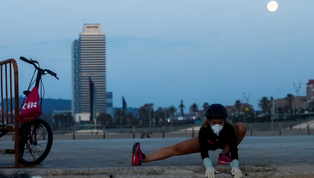 Una mujer hace ejercicio en la playa de la Mar Bella de Barcelona, una de las playas que a partir de hoy viernes los barceloneses pueden usar entre las 06.00 y las 10.00 horas para hacer deporte. EFE/Quique García