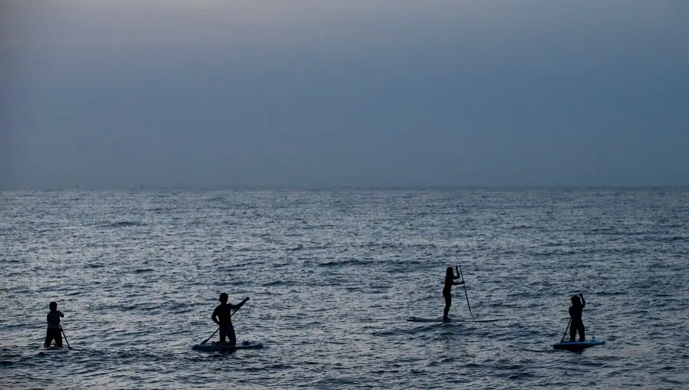 Varias personas practican paddle surf en la playa de la Mar Bella de Barcelona, una de las playas que a partir de hoy viernes los barceloneses pueden usar entre las 06.00 y las 10.00 horas para hacer deporte. EFE/Quique García