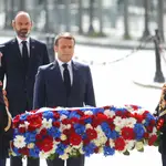 El presidente francés, Emmanuel Macron, acompañado por su primer minitro, Édouard Philippe, coloca una corona de flores en la tumba del Soldado Desconocido en el parisino Arco del Triunfo