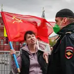 Una manifestante con la bandera de la hoz y el martillo se encara con un policía en la Plaza Roja de Moscú este pasado sábado