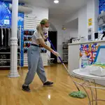 La dueña de una tienda de camisetas hace una limpieza en uno de los comercios de menos de 400 metros que han retomado su actividad con limitaciones de aforo y la puesta en marcha de medidas de higiene en la fase 1 de la desescalada