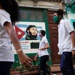 Varios estudiantes de Medicina caminan por delante de un cartel de Fidel Castro en La Habana