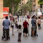 Varios padres y madres pasean con sus hijos por la plaza de Santo Domingo de Murcia