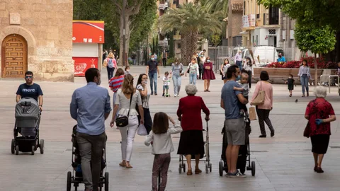Varios padres y madres pasean con sus hijos por la plaza de Santo Domingo de Murcia
