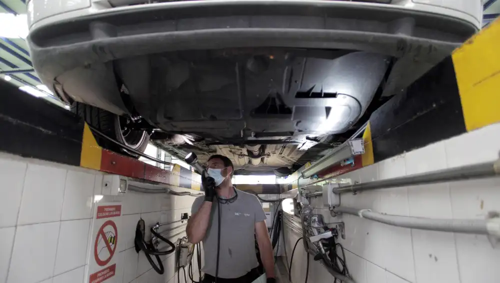 Un trabajador de la ITV revisa los bajos de un vehículo | Fuente: EFE/Cabalar