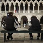 Gondoleros charlan en un banco a la espera de clientes en la Plaza de San Marcos de Venecia