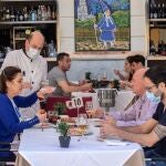 Un camarero atiende a una familia en una mesa de la terraza